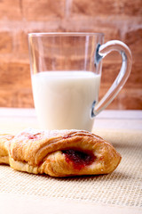 Easter breakfast with traditional hot cross bun with jam and glass with milk. From above on wooden table.