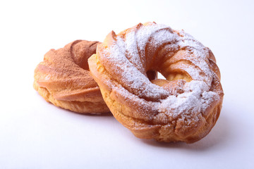 Chocolate and powdered sugar cream puff rings, choux pastry. Isolated on white background.