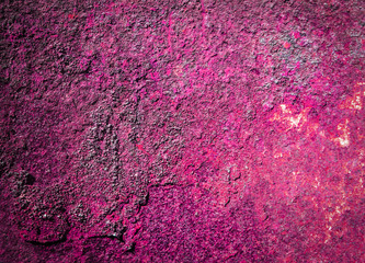 Texture of an old painted raspberry color wall with cracked plaster