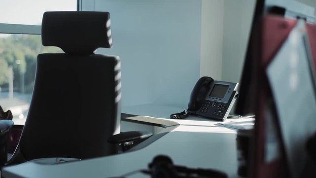 Black chair spinning in empty office. Desk with folders, colored notes. Indoors. Modern repair. Skyscraper. Working day interior view of a contemporary empty business office the chair returns phone
