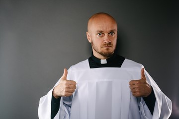 Catholic priest in white surplice and black shirt with cleric collar showing OK