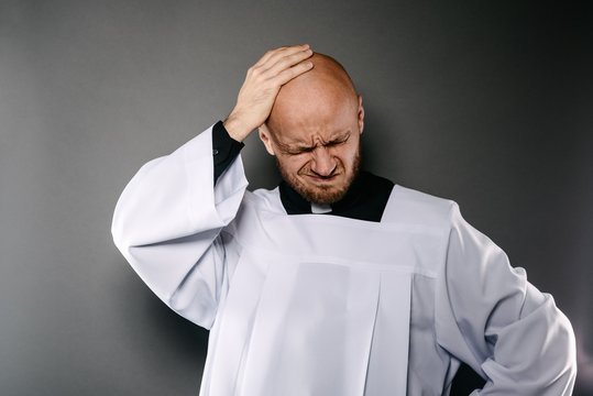 Confused catholic priest in white surplice