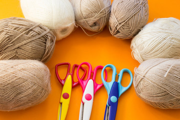 Balls of yarn in natural tones on an orange background. Copy space. Women's hobby and crafts. The concept of earning needlework.