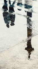 Reflection of couple in wet pavement front of Nelson's Column, Traflagar Square, London, UK