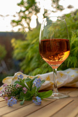 One cold rose wine glass served on outdoor terrace in garden with flowers