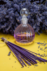 Natural healthy aromatherapy and home fragrance, purple lavender incense sticks and diffuser on yellow background with dried lavender flowers