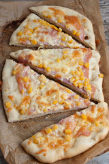 Colorful sliced homemade pizza for kids with cheese and sweet corn. Italian traditional food. Top view.