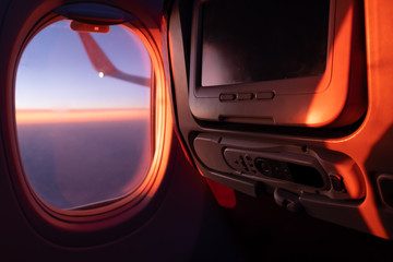 Seats, TV system and window inside an aircraft. Airplane interior in sunlight
