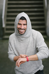 Motivated cheerful sportsman timing running workout. Sporty man training outside.