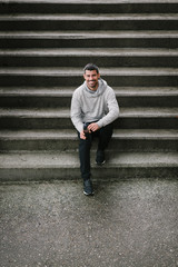 Sporty man taking a fitness or running workout rest for drinking water. Male athlete on urban training.