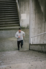 Urban athlete running upstairs. Sporty man working out outside and climbing stairs in winter.