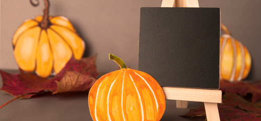 Autumn, halloween pumpkins and mini blackboard chalkboard and maple leaves. Grey backgroud, copy...