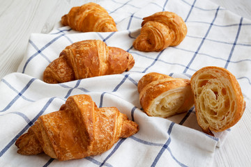 Fresh croissants on cloth on white wooden table, side view. Close-up.