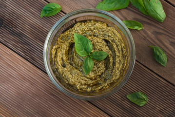 Basil pesto in glass bowl on a wooden table. Close up food.