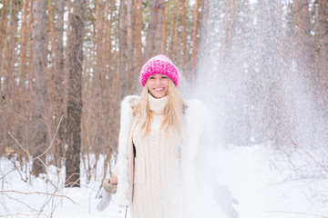 Happy young woman plays with a snow at snowy forest outdoor