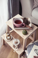 Plaids, a cup of hot tea, autumn decor, a book, a pumpkin on a wooden chair. Cozy, autumn decor. Autumn interior, sofa. Autumn. Winter.