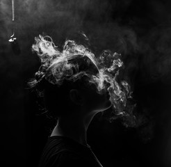 profile of a beautiful girl on a black background. The face of a girl exhaling smoke. Smoking...