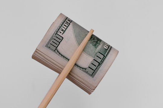 Bundle of dollars in chopsticks. Keeping money with sushi sticks. Photo bundles of dollars on a light background.
