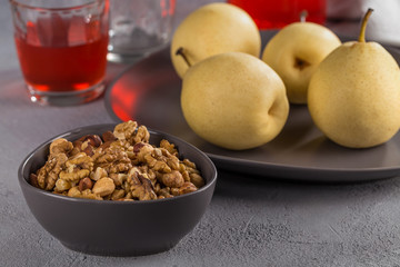 Mix of nuts of different varieties in a black bowl on the background of Japanese pears.