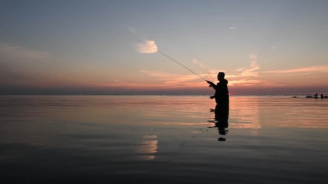 Ein Fischer beim fleigenfischen zum Morgengrauen oder Abendrot wirft seine leine im Windstillen Wasser aus