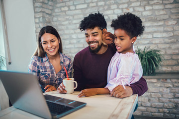 Girl and mixed race parents use laptop at home