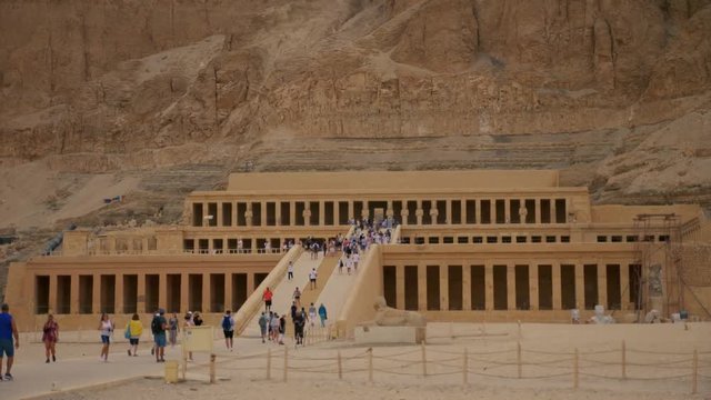 Tourists walking at the egyptian temple of queen hatshepsut. Front view of an ancient temple.