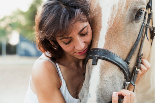 Woman cuddling riding horse