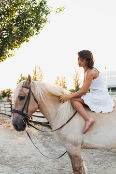 Barefoot woman sitting bareback on horse