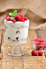 Yoghurt with oatmeal and fresh raspberries in a glass and mint leaves