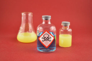 Vial of poison stock images. Vial with warning pictogram. Laboratory accessories. Chemical glass on a red background. Chemical glass containers with liquid