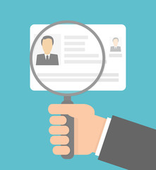 Hand holding magnifying glass over identity card or driver license