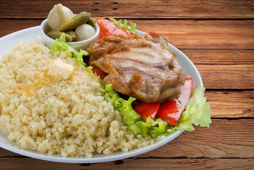 Millet porridge with chicken, pickles and vegetables. On a wooden background