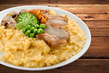 Wheat porridge with pork and vegetables. On a wooden background