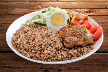 Buckwheat porridge with pork and vegetables. On a wooden background