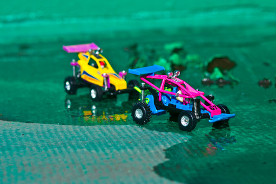 Two small off-road cars are running in a rugged green zone.