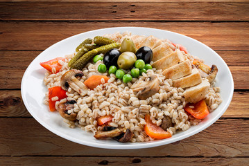 Pearl barley with chicken and vegetables. On a wooden background