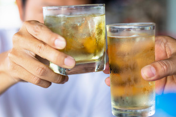 Close up two men clinking glasses of whiskey drinking alcoholic beverage together.