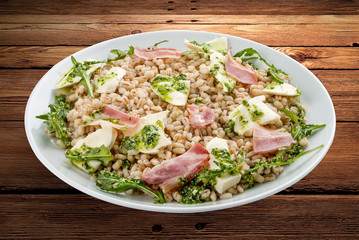 Pearl barley with ham and cheese. On a wooden background