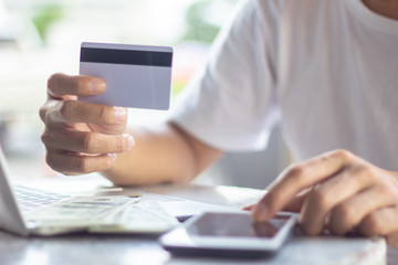 Man using mobile phone and laptop shopping online with credit card. Man holding credit card using smart phone for purchase or buy and sell products & services.