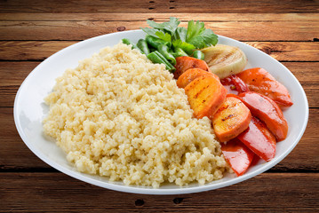 Millet porridge with grilled vegetables. On a wooden background