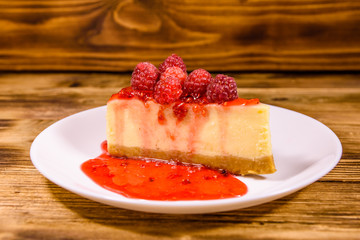 White plate with cheesecake New York and raspberries on wooden table