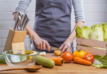 The hands of a woman cook prepare a salad with fresh vegetables. Healthy food. White background