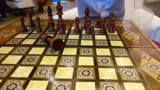 Man arranging chess pieces on a wooden board preparing to play
