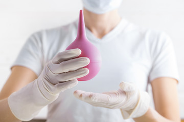 Enema in the doctor's hand on the white background.