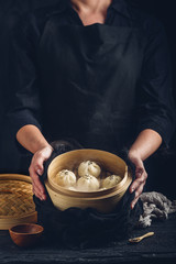 Woman presenting dim sum dumplings in steamer