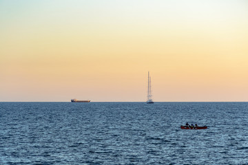 Sunset of a lovely day in the bay of Naples, Italy. Some boats navigate quietly on the calm water in a minimal romantic view