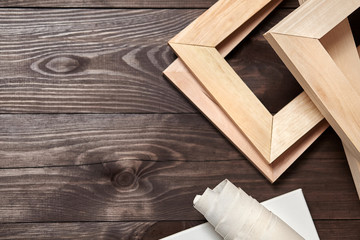 Wooden stretchers and a rolled canvas lying on a dark wooden background with copy space. Wood products: Subframes. Top view