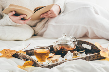 Woman and warming tea in bed. Window light
