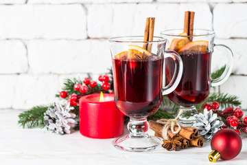 Mulled wine in glass mug with fruit and spices on white.