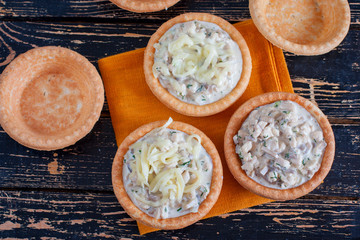 Step by step cooking tartlets with mushrooms, chicken and cheese on a wooden table - preparing the necessary ingredients, top view